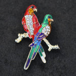 Two enamel/crystal Parrots on perch, A6/11-13